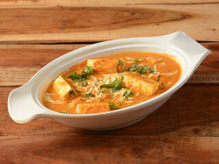 Paneer Masala or Cheese Cottage Curry, is a famous indian dish, served over a rustic wooden background, selective focus