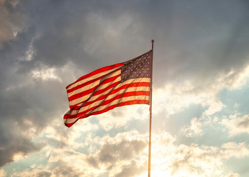 Back lit American flag waving at sunset