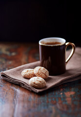 Amaretti (Italian biscuits) and a cup of coffee on rustic wooden background. Close up. 