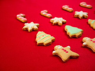 Funny gingerbread man with protective mask for Santa Claus. Different shapes of homemade Christmas cookies on red background: gingerbread man, Christmas tree, snowflake, candy stick. Normal new 2021. 