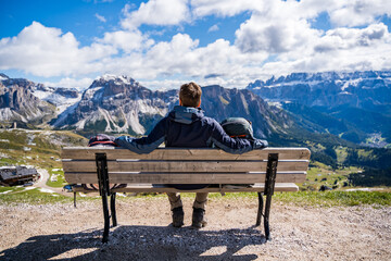 person sitting on a bench in the dolomites mountains