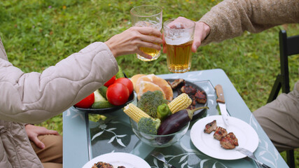 During a picnic in the country, a man and a woman clink glasses with beer, celebrate the holiday