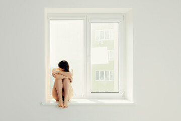 Sad woman hug her knee and cry on window. Girl in depression. Sadness and pain. 