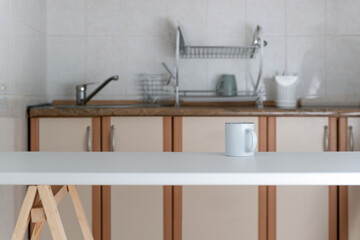 Minimalist kitchen design in light colors. Modern kitchen interior. Cup on table