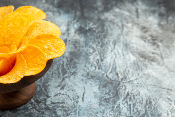 Half shot of potato chips decorated like flower shaped in a brown bowl on the right side of gray background