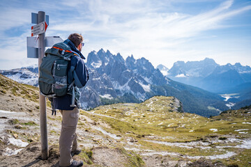 hiker with backpack looking on the dolomites mountains