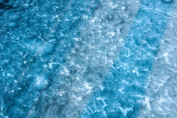 Abstract ice texture. Cracks in a piece of blue ice. Wave.