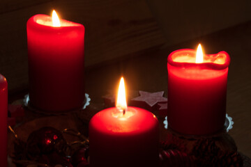 Rote brennende Kerzen auf einem Adventsgesteck. Es ist der dritte Advent. Bald ist Weihnachten.