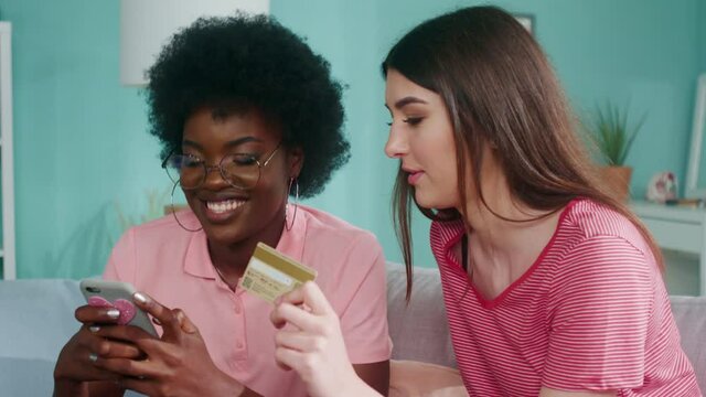 Young women stay home, preferring online shopping, enter credit card number to make a purchase, enjoy sales, give five to celebrate good deal, Close up, Slow motion.