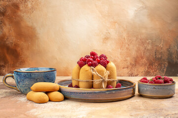 Vertical view of freshly baked soft cake with fruits and tea in a blue cup on mixed color table