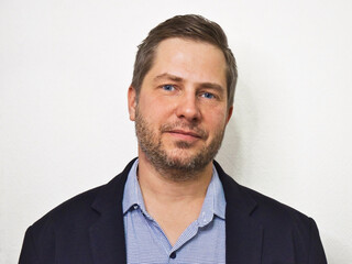 Portrait of caucasian unshaven business man watching in camera isolated on white background. Casual style man in jacket and shirt with no tie.