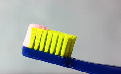 Blue toothbrush with green bristles close-up, pink toothpaste. Dental hygiene and care products...