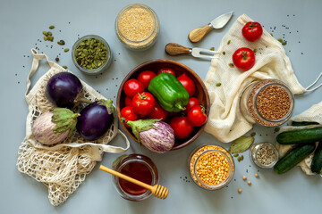 Zero waste healthy food-cereals, seeds, vegetables flat lay on grey background. Groceries in textile bags,glass jars, wooden bowl. Eco friendly plastic free low waste lifestyle.