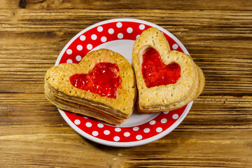 Heart shaped puff cookies with jam on a wooden table. Dessert on Valentine`s Day