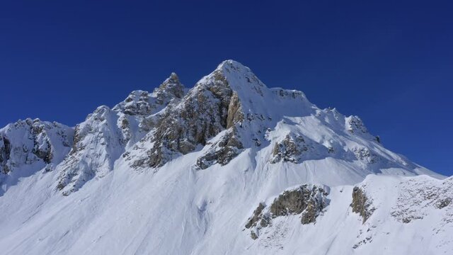 Mountain in winter - Drone turning around a snowy mountain in Tignes - Val d'Is&egrave;re, with a blue sky in background