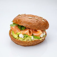 Bagel with salmon and herbs on a white background.
