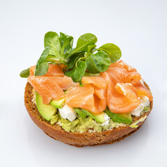 Bagel with salmon and herbs on a white background.
