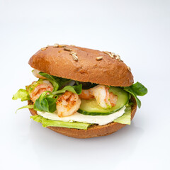 Bagel with shrimp and herbs on a white background.
