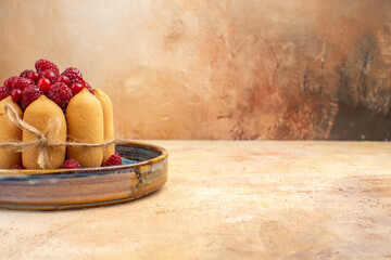 Side view of freshly baked gift cake with fruits on a blue tray on mixed color background