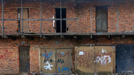 Painted rusty old warehouse doors on two-storey brick building. Background for design. Space for text.