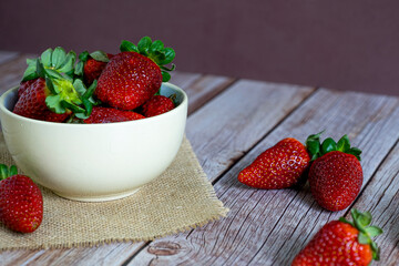 Strawberries in a bowl on top of a wooden table