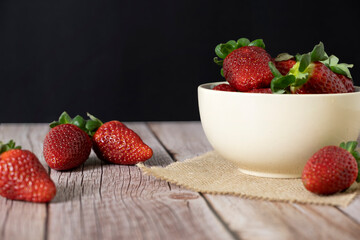 Strawberries in a bowl on top of a wooden table
