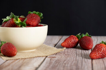 Strawberries in a bowl on top of a wooden table