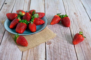 Strawberries in a bowl on top of a wooden table