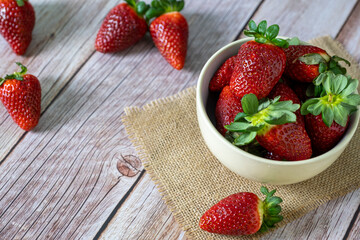 Strawberries in a bowl on top of a wooden table