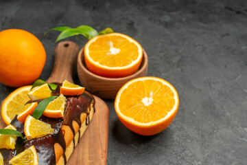Close up view of tasty cakes whole and cut lemons on cutting board on black table
