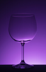 Empty wine glass on purple background.