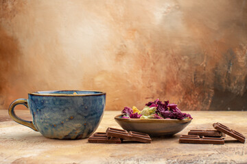 A cup of hot herbal tea flowers and chocolate bars on mixed color background stock image