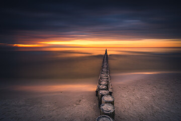 The Baltic breakwaters in Łeba with the setting sun. Long exposure photography.