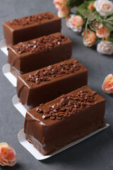 Four mousse desserts covered with chocolate on a dark gray background. Vertical format