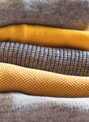 Yellow illuminated color and gray winter sweaters stack. Trendy fashion autumn warm and cozy clothes.