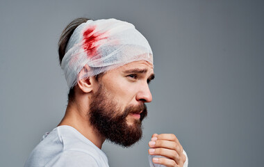 man with bandaged head and blood concussion gray background medicine