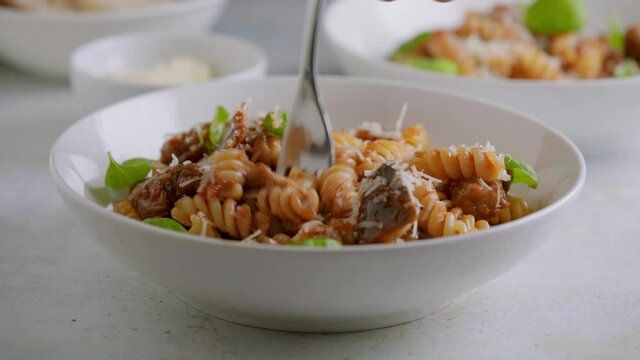 Someone eat fusilli pasta with tomato sauce, roasted eggplant and parmesan cheese
