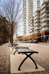 Calgary Alberta Canada, dec 02, 2020: Metal park benches on a brick sidewalk in the new downtown central East Village apartment area.