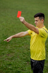 Angry football referee showing a red card and pointing with his hand on penalty