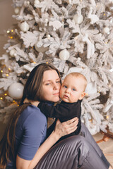 Obraz premium Mom with a small son near a beautiful Christmas tree in his house