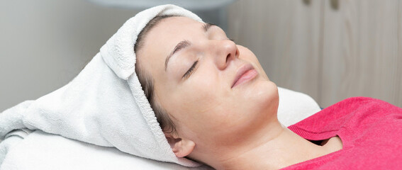 Face skin care. Beautician applying beauty oil mask on face using brush In spa salon