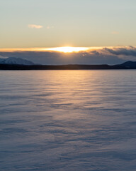 Impressive sunset over a winter frozen lake snowy covered in northern Canada during December when the sun doesn't rise for long. Days are short, snow capped mountains, tourism, tourist, explorers. 