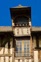 Dormer mansard window and glass paned window of half-timbered house against blue sky in Place Sainte-Anne, Rennes, Brittany, France