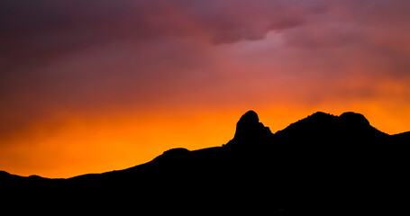Vivid Sunset with Mountain Horizon Silhouette Rays of Light in Purple and Orange