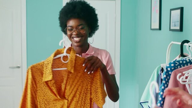Young stylish women, Afro-American and Caucasian white, are getting ready to a party, choosing dresses, having fun, anticipating great evening, Foreground, Slow motion.