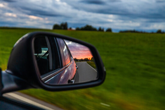 Left driving mirror of car during sunset golden hour