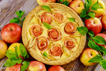 Fresh apple pie with decoration like a rose on wooden background.