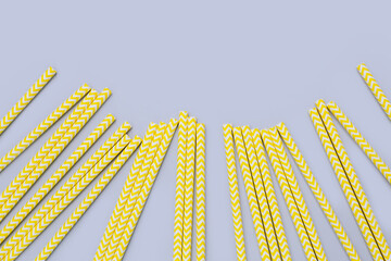 Background of yellow cocktail party paper straws on gray background. Trendy colors of the year 2021.