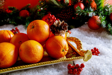 Fototapeta na wymiar Seasonal oranges in christmas tray with ornament.