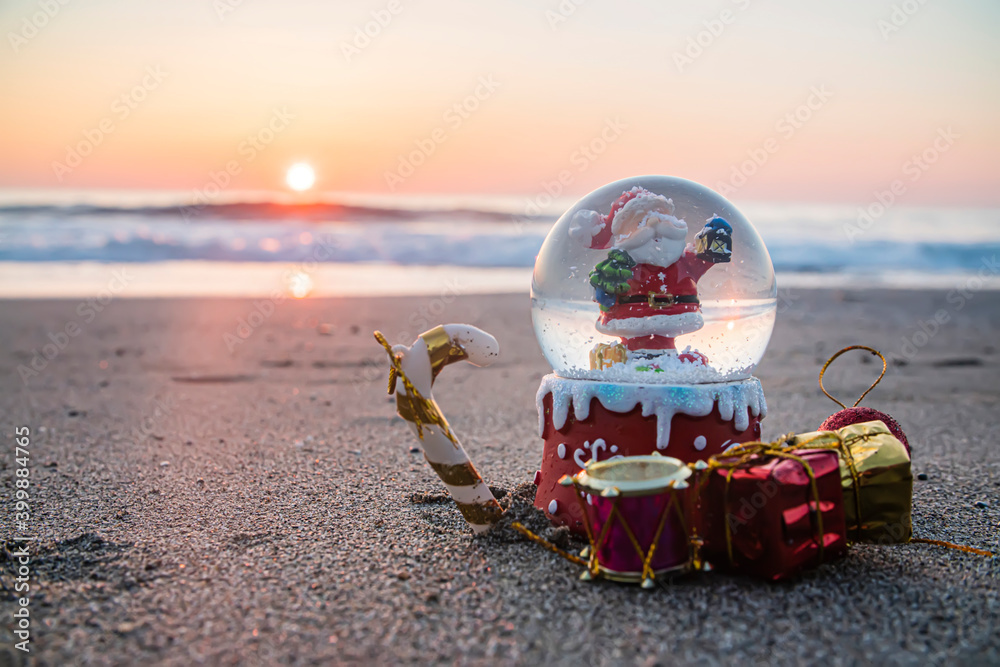 Wall mural christmas snow ball globe on the beach, by the sea as a symbol of christmas at resort